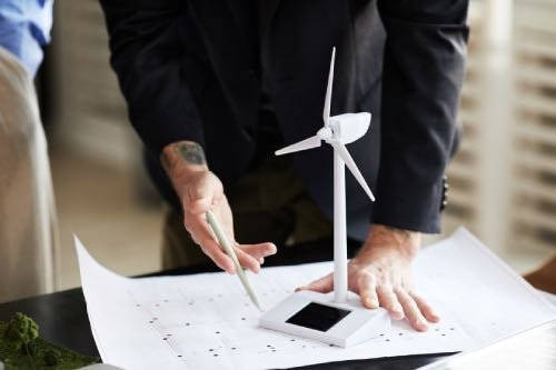 Ein Ingenieur hält eine kleine Windturbine, die erneuerbare Energie und nachhaltige Technologie symbolisiert.